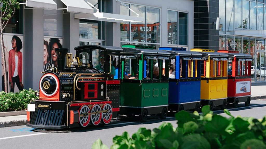 Maxi Express trackless train driving through a modern shopping mall with families and children on board